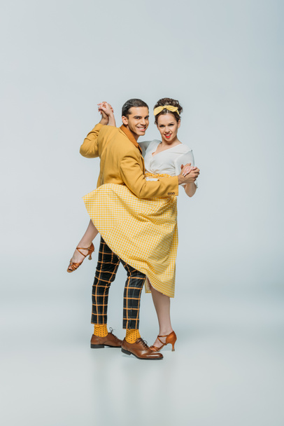 smiling dancers holding hands while dancing boogie-woogie on grey background - 写真・画像