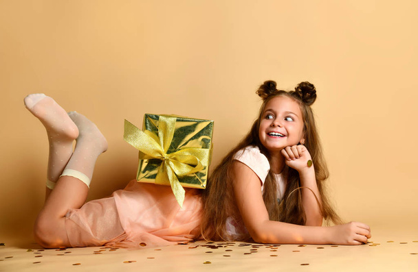 beautiful little girl lying on the floor with a gift box in the studio - Foto, Imagem