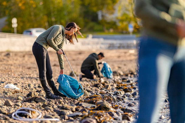 Dedykowani wolontariusze sprzątający plażę w słoneczny dzień - Zdjęcie, obraz