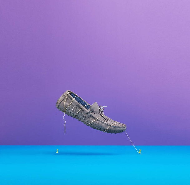 flying gray male moccasin held by threads on a blue-violet background. - Photo, Image