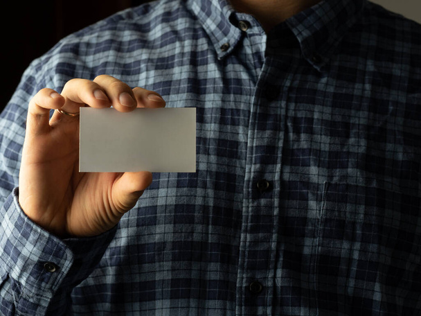 un hombre con una camisa a cuadros pone una tarjeta de visita en el bolsillo de su camisa. espacio de copia
 - Foto, Imagen