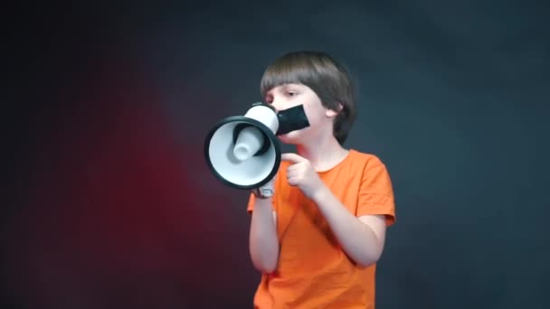 A boy with a sealed mouth shouts into a megaphone. - Záběry, video