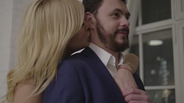 long haired lady kisses handsome bearded man in suit - Materiał filmowy, wideo