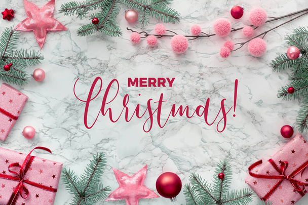 Panoramic Christmas flat lay on white marble with border made from wrapped gift boxes, natural green fir twigs, red and pink trinkets. Text "Merry Christmas". - Fotoğraf, Görsel