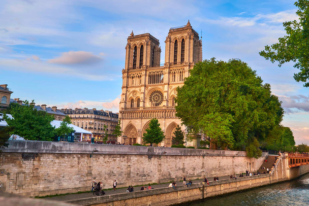 Paříž, Francie - 14. května 2017: Katedrála Notre-Dame, jedna z vrcholných atrakcí Paříže, brzy večer, kde si mnoho lidí užívá klidného večera u řeky Seiny. - Fotografie, Obrázek