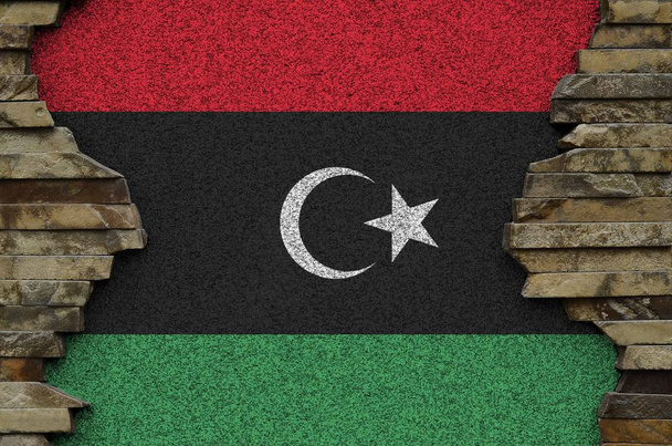 Eine libysche Flagge in Farbtönen auf alten Steinmauern aus nächster Nähe. Texturiertes Banner auf Felswand Hintergrund - Foto, Bild