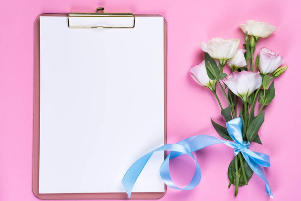 Ελάχιστη σύνθεση με άνθη ευστώματος σε φάκελο με πρόχειρο σε ροζ φόντο, πάνω όψη. Ημέρα του Αγίου Βαλεντίνου, γενέθλια, μητέρα ή γαμήλια κάρτα - Φωτογραφία, εικόνα