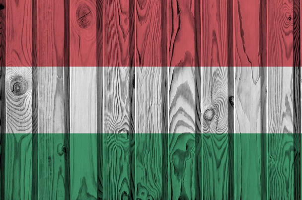 古い木製の壁に明るい塗料の色で描かれたハンガリーの旗が閉じます。ざらざらとした背景に書かれた旗 - 写真・画像