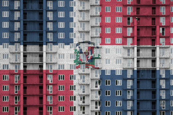 Dominikánská republika vlajka vyobrazená v barvách na vícepodlažní obytné budově ve výstavbě. Texturovaný banner na velké cihlové zdi pozadí - Fotografie, Obrázek