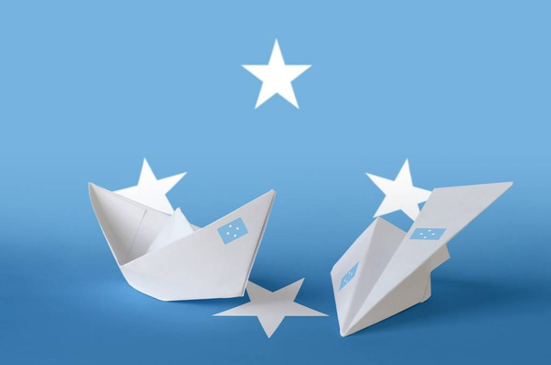 Mikronéziai zászló ábrázolt papír origami repülőgép és hajó. Keleti kézműves művészeti koncepció - Fotó, kép