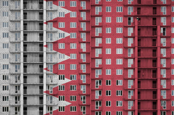 Bandera de Bahréin representada en colores de pintura en un edificio residencial de varios pisos en construcción. Banner texturizado sobre fondo de pared de ladrillo grande
 - Foto, Imagen