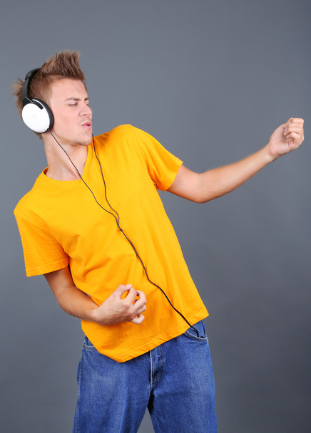 Handsome young man listening to music on grey background - Foto, Imagem