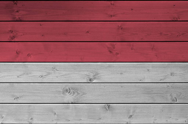 Monaco zászló ábrázolt élénk festék színek a régi fából készült fal közeli. Texturált banner durva háttér - Fotó, kép