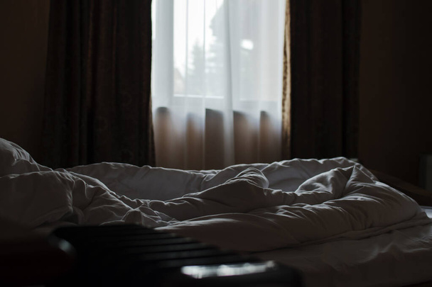 Незаправленная кровать в номере отеля. Раннее утро, свет из окон. Ранним утром, тень
. - Фото, изображение