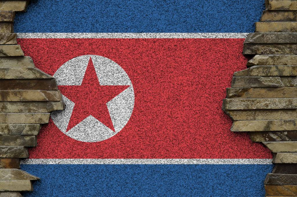 Észak-Korea zászlaját festett színek régi kő fal közeli. Texturált banner a sziklafal háttér - Fotó, kép