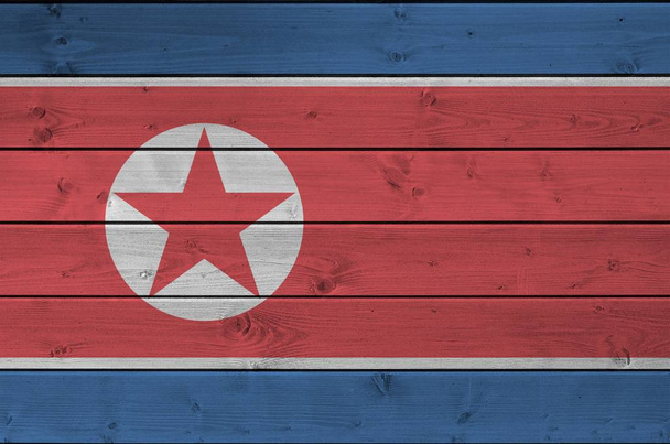 Észak-Korea zászló ábrázolt élénk festék színek a régi fából készült fal közeli. Texturált banner durva háttér - Fotó, kép