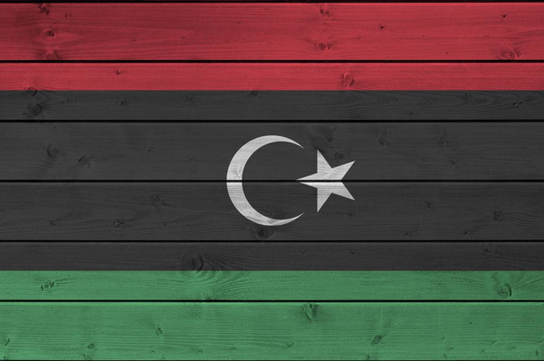 Σημαία Λιβύης απεικονίζεται σε φωτεινά χρώματα μπογιάς σε παλιό ξύλινο τοίχο από κοντά. Υφή banner σε πρόχειρο φόντο - Φωτογραφία, εικόνα