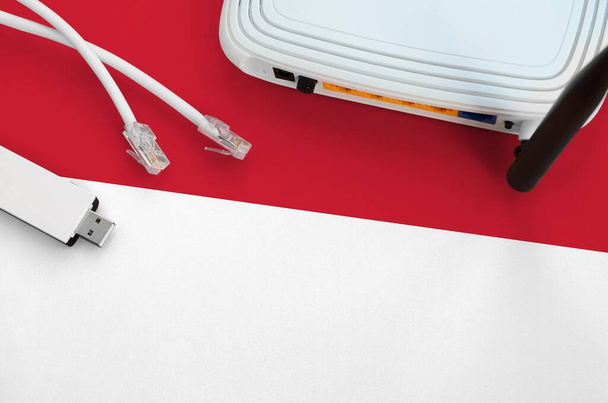 Bandera de Mónaco representada en la mesa con cable rj45 internet, adaptador inalámbrico usb wi-fi y router. Concepto de conexión a Internet
 - Foto, imagen