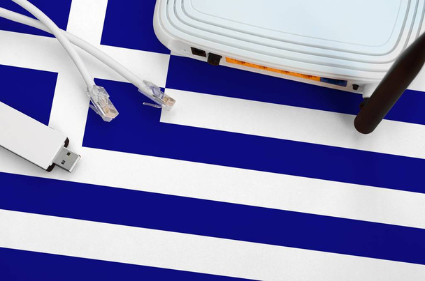 Griekenland vlag afgebeeld op tafel met internet rj45 kabel, draadloze usb wi-fi adapter en router. Internetaansluitingsconcept - Foto, afbeelding