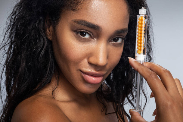 Cute Afro American woman with curly hair keeping syringe in hand - Zdjęcie, obraz