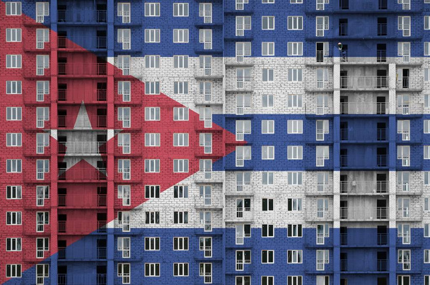 建設中の複数階建ての住宅ビルにペイントカラーで描かれたキューバの旗。大きなレンガの壁の背景にテクスチャバナー - 写真・画像
