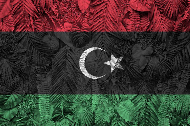 libysche Flagge auf vielen Blättern von Monsterpalmen. trendiger modischer Hintergrund - Foto, Bild