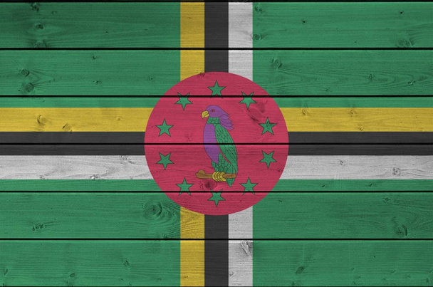 Dominika vlajka vyobrazena v jasných barvách na staré dřevěné zdi zblízka. Texturovaný nápis na hrubém pozadí - Fotografie, Obrázek