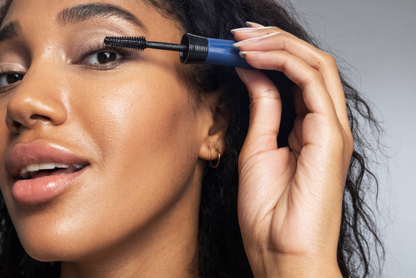 Woman dyeing eyelashes with mascara against light background - Foto, immagini