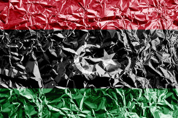 Bandera de Libia representada en colores de pintura sobre papel de aluminio arrugado brillante de cerca. Banner texturizado sobre fondo rugoso
 - Foto, imagen