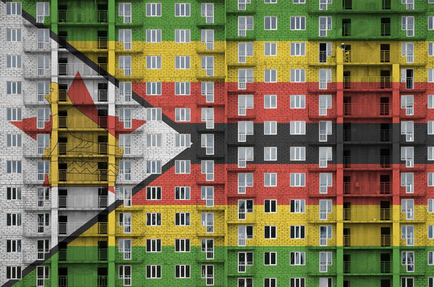 Flaga Zimbabwe przedstawiona w kolorach farby na wielopiętrowym budynku mieszkalnym w budowie. Baner teksturowany na dużym ceglanym tle ściany - Zdjęcie, obraz