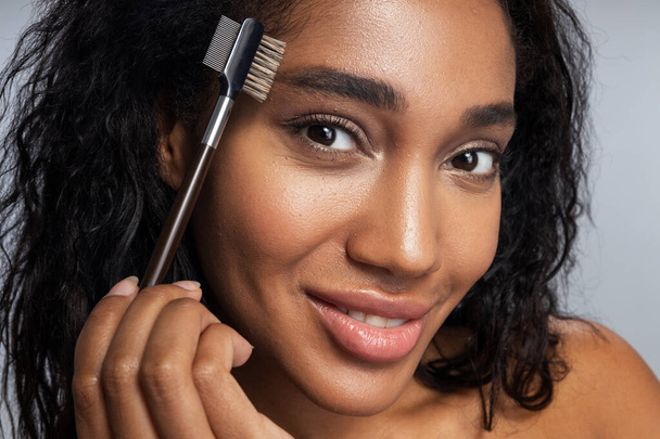 Gorgeous attractive Afro American woman brushing her eyebrows - Fotoğraf, Görsel