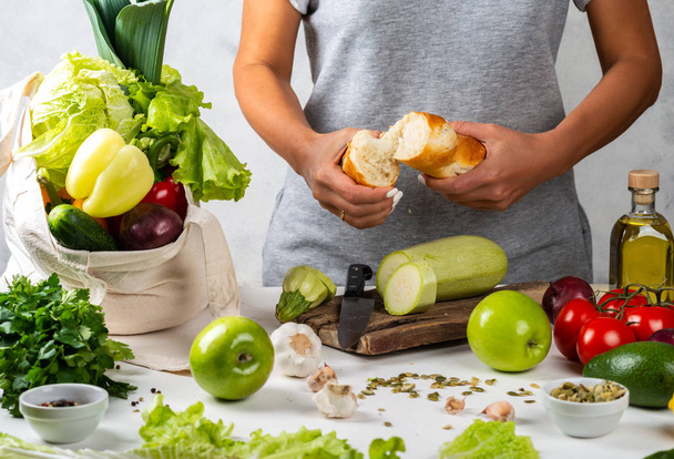 Frau wird gesundes Essen kochen und umweltfreundliche Stofftaschen voller frischem Gemüse auf dem Küchentisch haben. Zero Waste Purchase Konzept. Gesundes Ernährungskonzept. - Foto, Bild