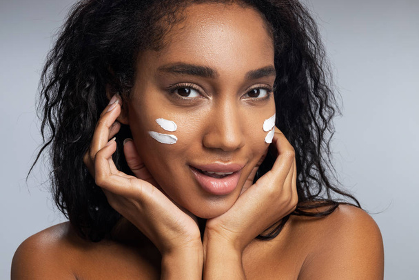 Sexy young Afro American woman applying facial cream - Foto, Imagem