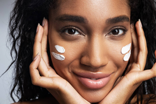 Sexy smiling Afro American woman applying facial cream - Photo, Image