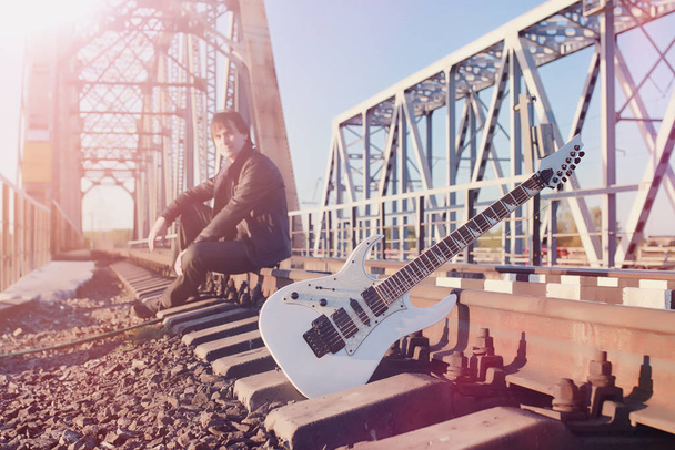 Um homem com uma guitarra eléctrica na estrada de ferro. Um músico em uma le
 - Foto, Imagem