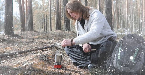 Een man in een campagne drinkt thee. Een jonge reiziger in de bossen ca - Foto, afbeelding