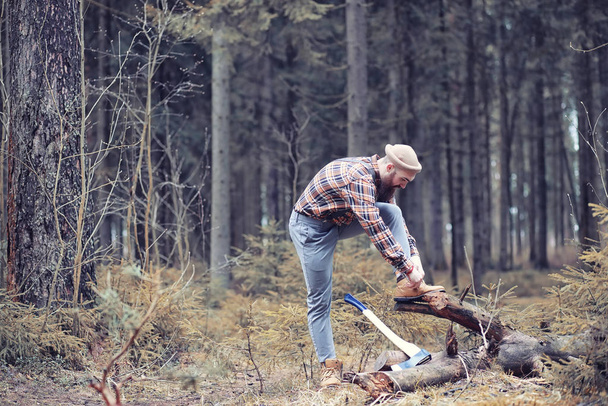 Ein bärtiger Holzfäller mit einer großen Axt untersucht den Baum vor dem Fällen - Foto, Bild
