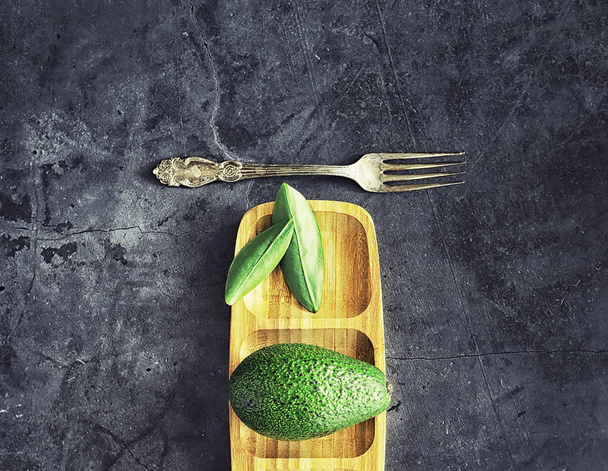 Avocado cooking recipes. Ripe green avocado on a wooden cutting  - Foto, afbeelding