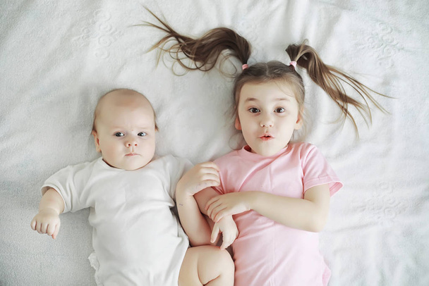 Dzieci leżą na łóżku obok noworodka, młodą siostrę. - Zdjęcie, obraz