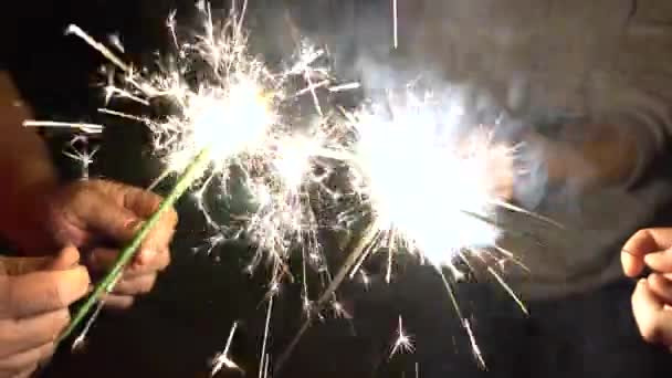 Egy baráti társaság együtt gyújtott csillagszórót. Az emberek készülnek az ünnepekre és a bengáli tüzekre. A baráti társaság körforgásba kezdett. Szikrázó kéz közelről - Felvétel, videó