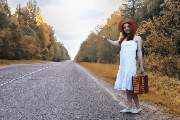 Φθινοπωρινό κορίτσι του πάρκου με λευκό φόρεμα και μια ψάθινη βαλίτσα. - Φωτογραφία, εικόνα