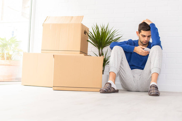 young man in the apartment with moving and mobile phone - Foto, Imagen