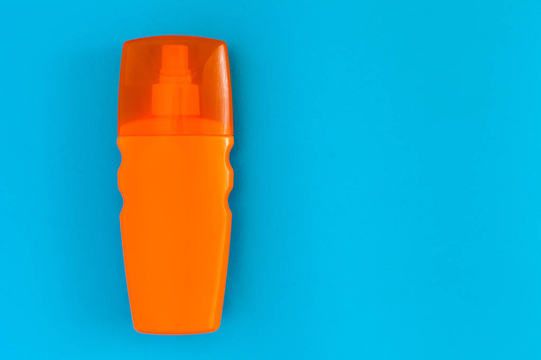 orange bottle with a spray of sunblock for tanning lies on a blue background top view, nobody. - Valokuva, kuva