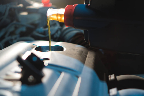 Engine oil change. Fresh engine oil pouring from the canister into the automobile engine. - Foto, immagini