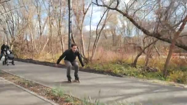 Desporto jovens pais com uma criança caminhar no outono ensolarado parque em patins. O pai vai à frente e faz uma acrobacia de salto. Movimento lento
. - Filmagem, Vídeo