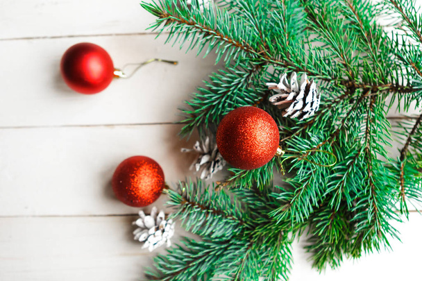 Spar takken met kegels en rode kerstballen op witte houten ondergrond. Kerst- of nieuwjaarsconcept - Foto, afbeelding