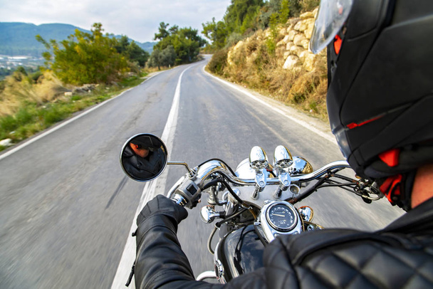 Uomo in moto e in viaggio su una strada di campagna vuota. La moto focalizzata e la strada offuscata movimento
. - Foto, immagini