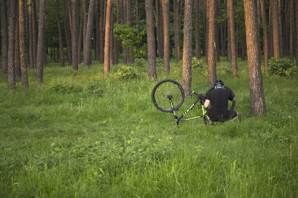 Kiev Ukraine - 22 mai 2019 : Jeune homme cycliste en vêtements de sport et casque de protection réparer la chambre à air de roue de vélo dans le parc
 - Photo, image