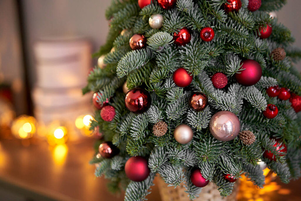 Beautiful small Christmas tree on wooden table. Happy mood. Garland lamp bokeh on background. Wallpaper. Danish pine and fir, Nobilis - Φωτογραφία, εικόνα