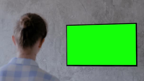 Koncept zelené obrazovky - žena sledující ploché smart led TV se zeleným displejem - Záběry, video